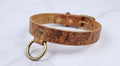 A brown leather collar with a floral pattern and a metal ring attached to it.