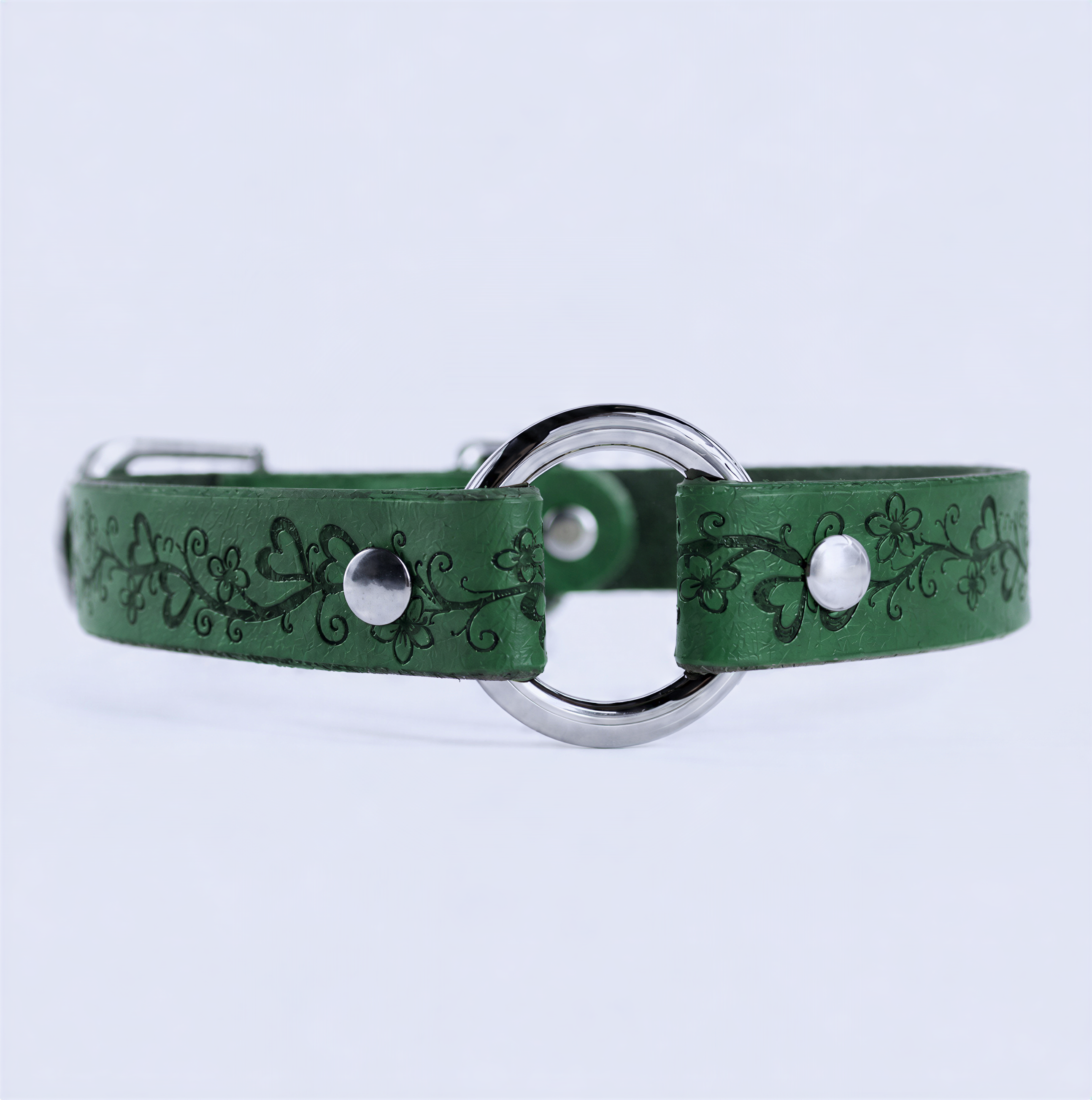 A green leather collar with a metal ring and decorative floral patterns.