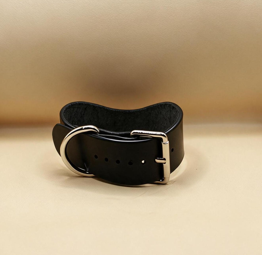 A black leather belt with a silver buckle is shown against a beige background.