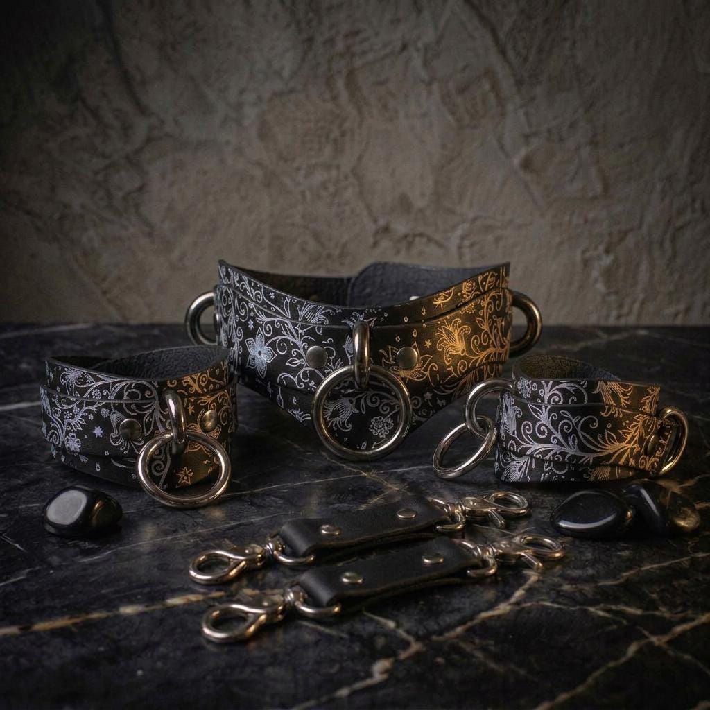 a collection of black and white leather accessories, including a choker necklace, bracelets, and straps, arranged on a dark surface.