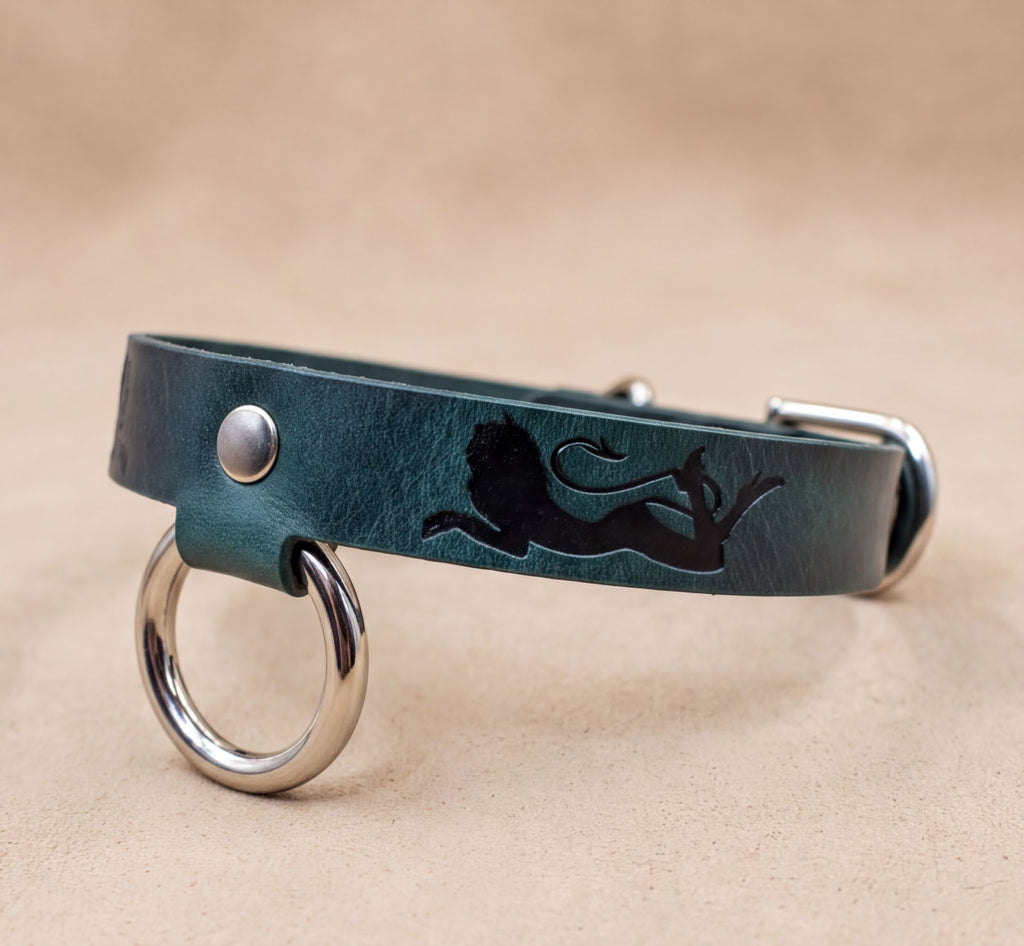 A green leather dog collar with a lion silhouette and metal rings on the ends.