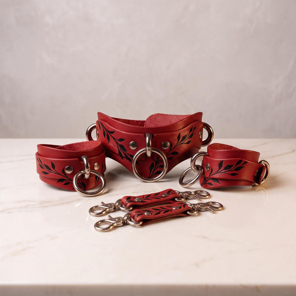 a set of red leather straps with black leaf designs, arranged on a white marble surface.