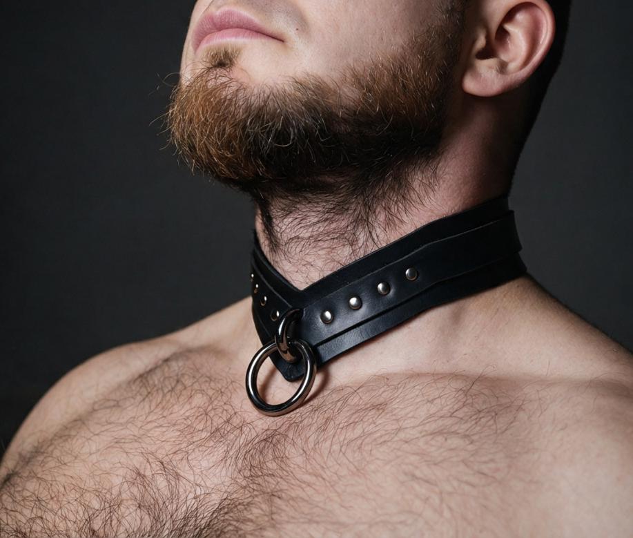 A close-up of a man's neck and chest area, with a black leather choker collar featuring metal rings and studs.