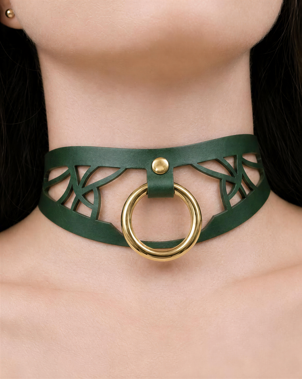 A close-up of a woman's neck wearing a green leather choker necklace with a gold ring.