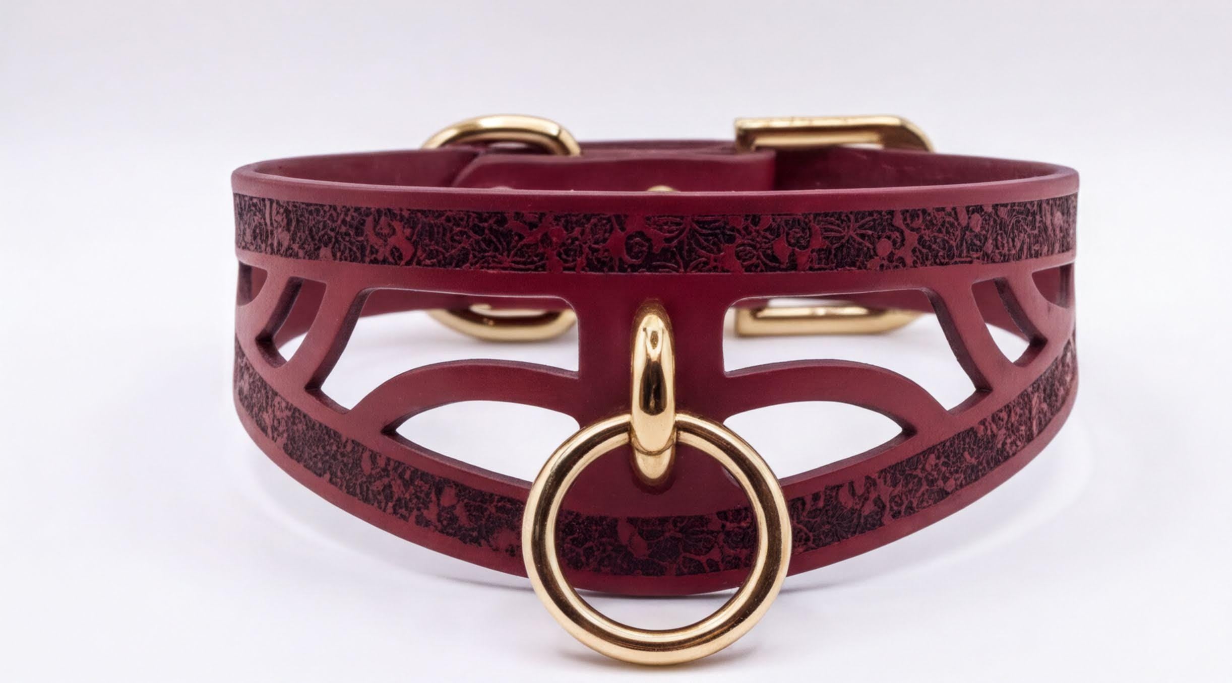 A burgundy leather choker collar with a gold-colored metal ring and buckle.
