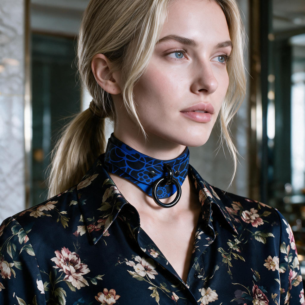 A woman with blonde hair wearing a blue choker necklace and a floral print blouse, looking off to the side.