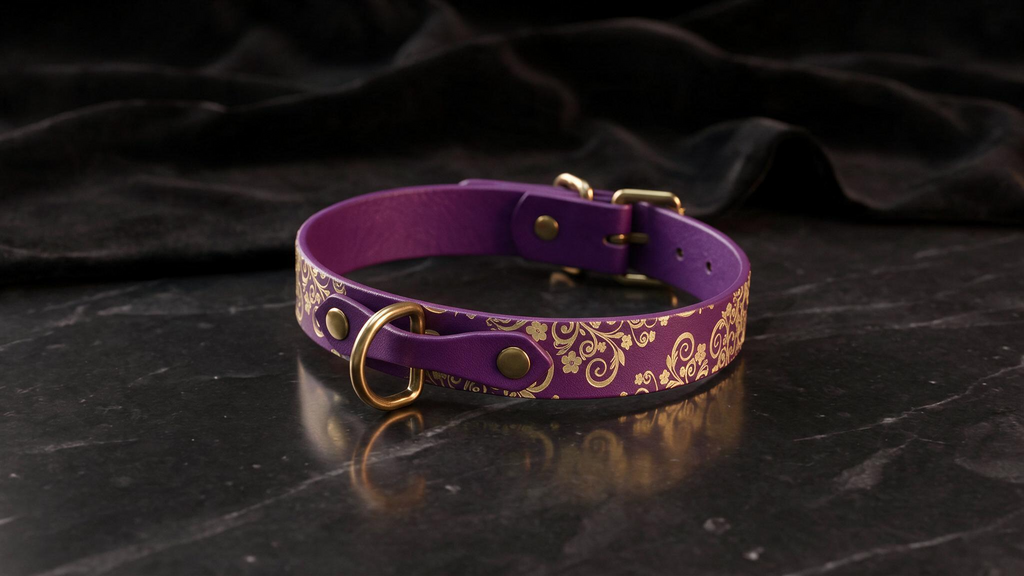 A purple leather collar with gold floral patterns and a gold-colored buckle is displayed on a black marble surface.