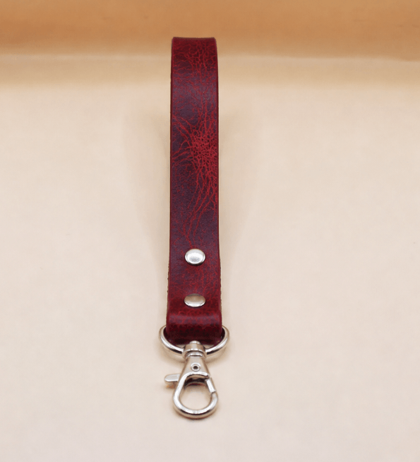 A red leather strap with a metal clasp and hook attached to it.