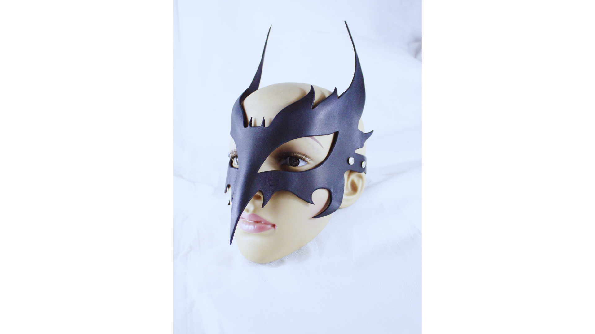 A mannequin head wearing a black mask with a unique, winged design.