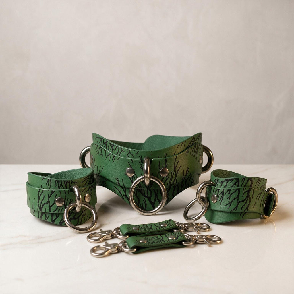 A set of green leather straps with metal rings and buckles, arranged on a white surface.