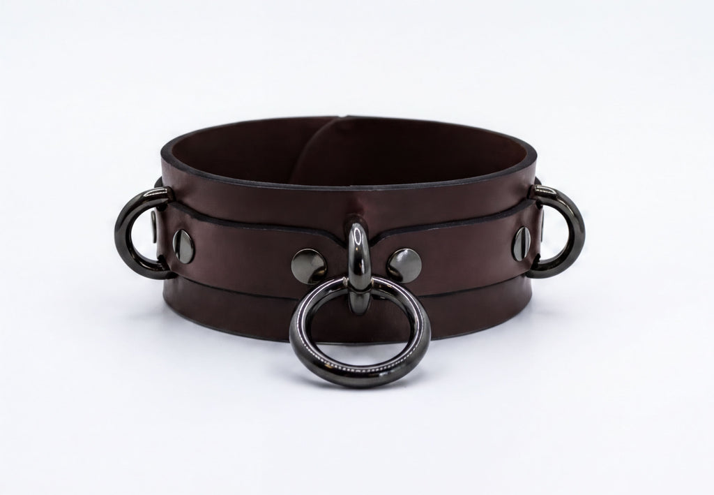 A brown leather choker collar with metal rings and buckles.
