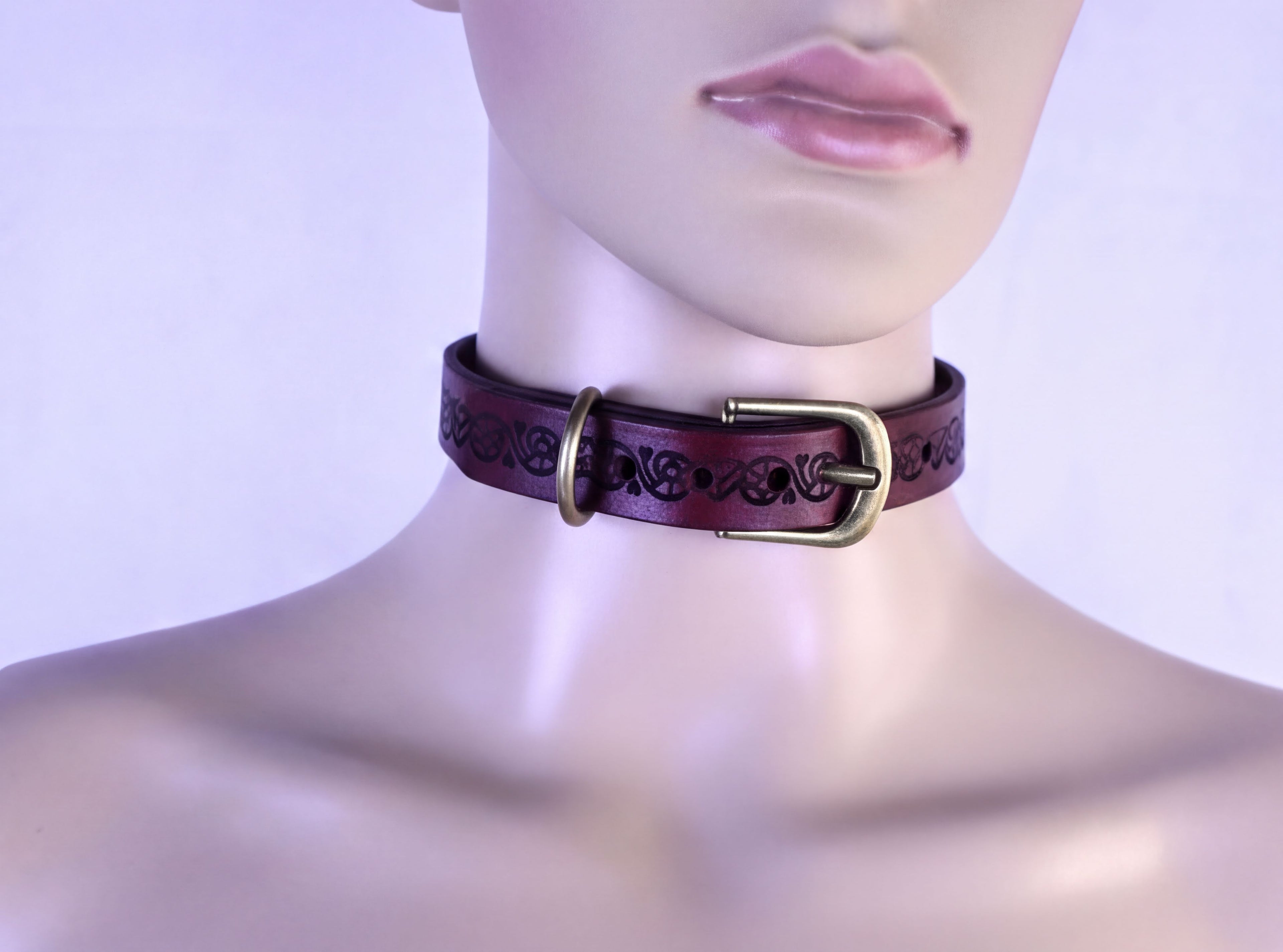 A mannequin head wearing a purple leather choker necklace with a brass buckle.