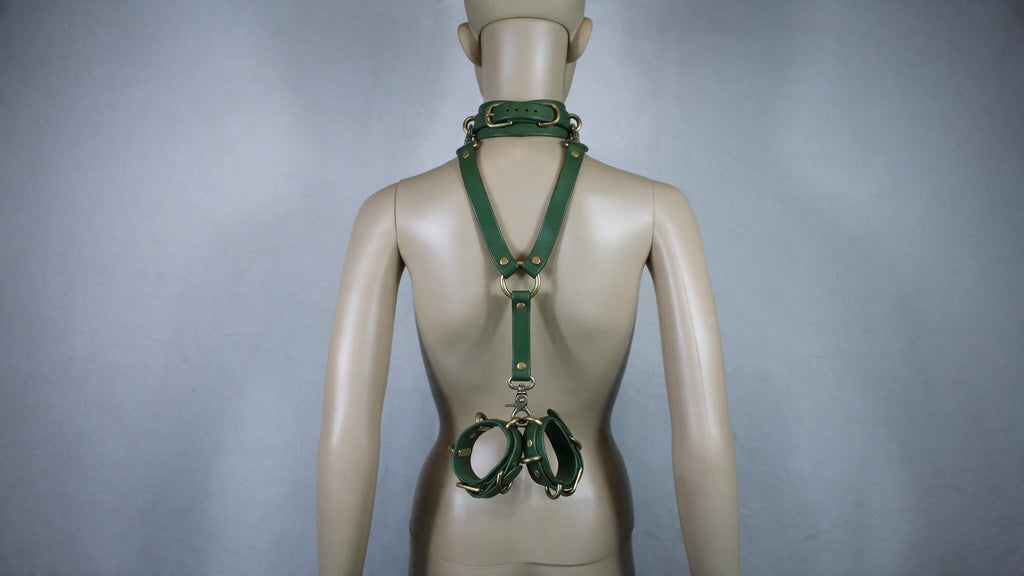 A mannequin wearing a green leather harness with a collar and straps, which appears to be a form of BDSM or BDSM-related accessory.