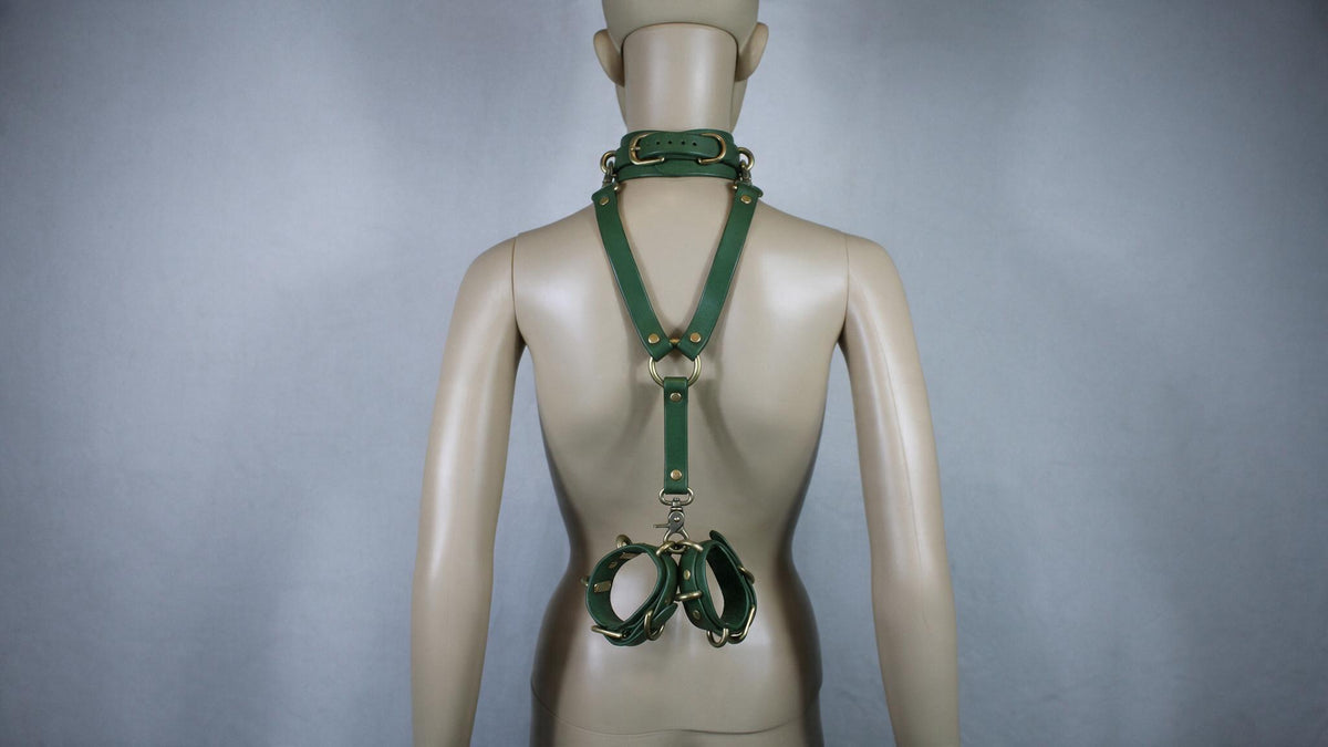 A mannequin wearing a green leather harness with a collar and straps, which appears to be a form of BDSM or BDSM-related accessory.