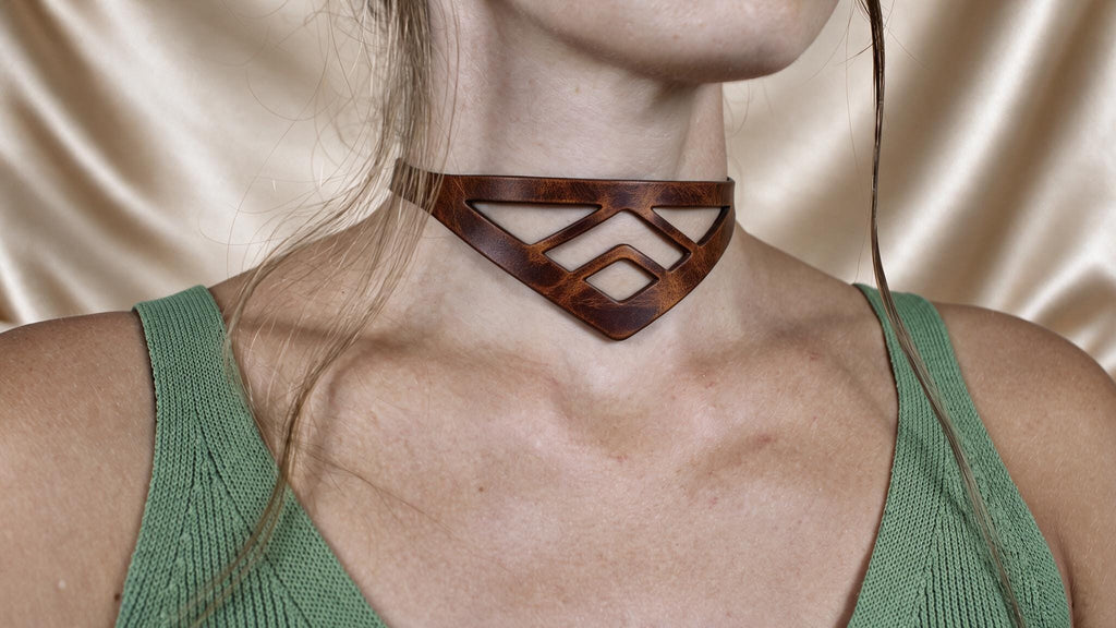 A close-up of a woman wearing a choker necklace with a geometric pattern.