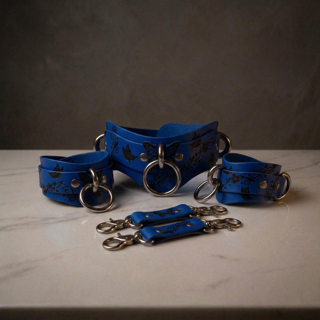 A set of blue leather choker necklaces with metal rings and clasps, arranged on a white marble surface.