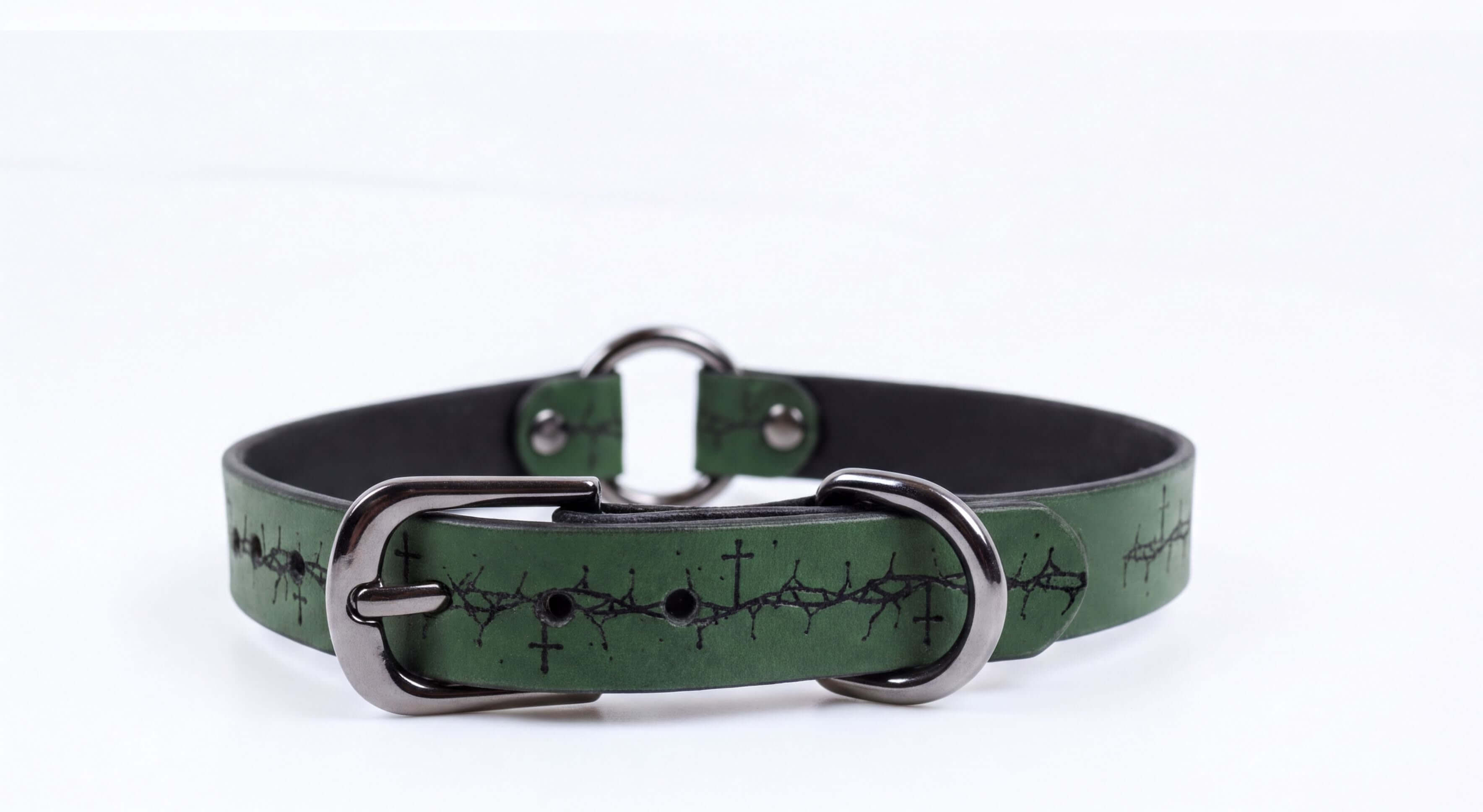 A green leather collar with a metal buckle and a design of crosses on the surface.