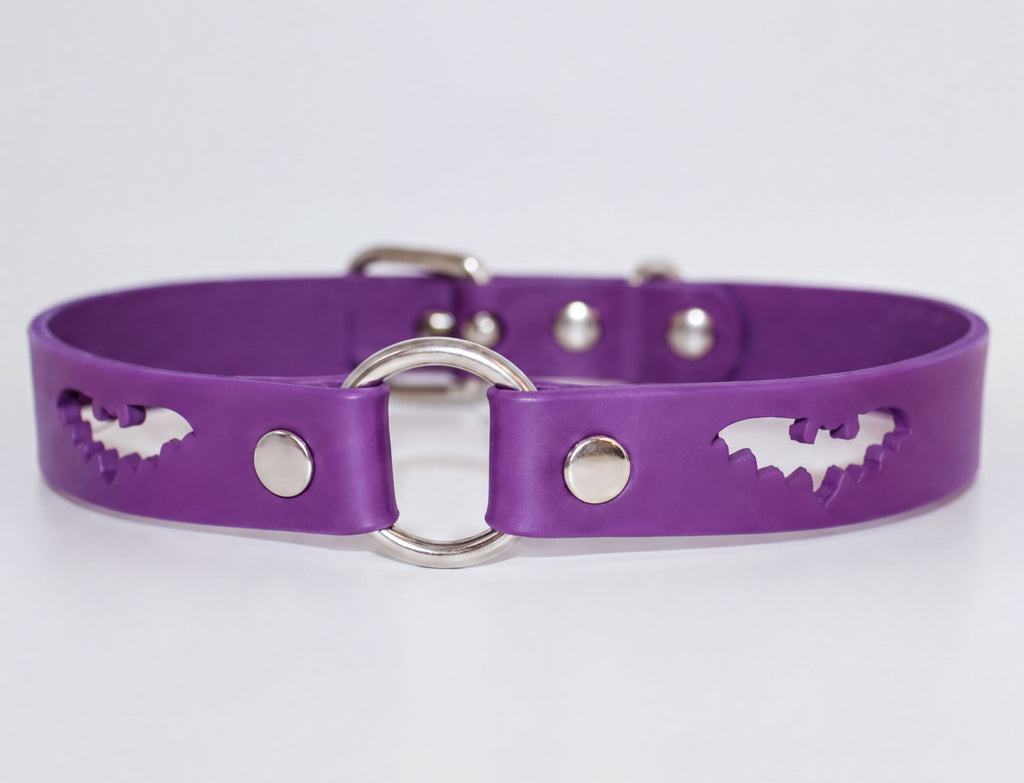 A purple leather dog collar with bat cutouts and metal rings.