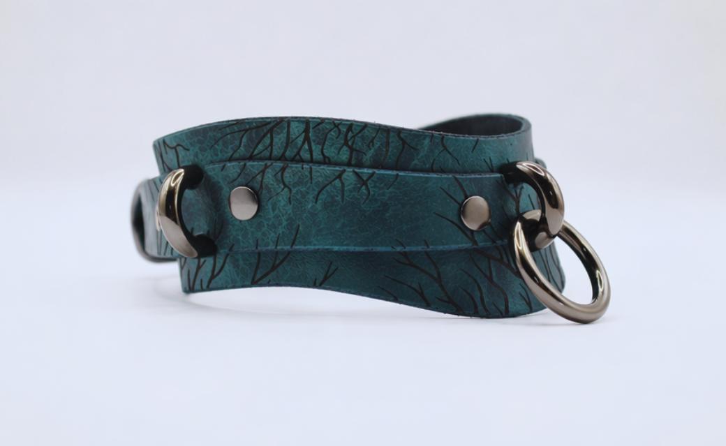 A dark green leather choker necklace with metal rings and a metal clasp.