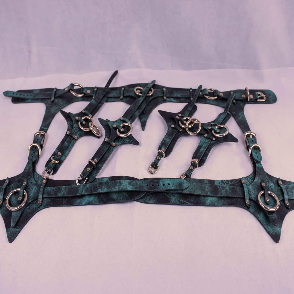 A collection of dark green leather straps with metal studs and buckles, arranged in a grid-like pattern.