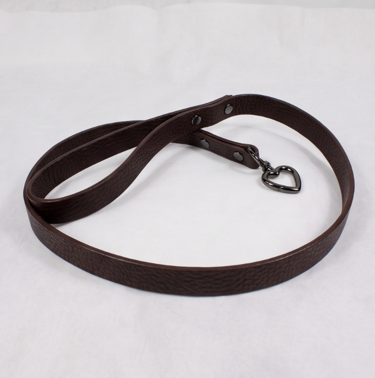 A brown leather dog leash with a heart-shaped charm attached.