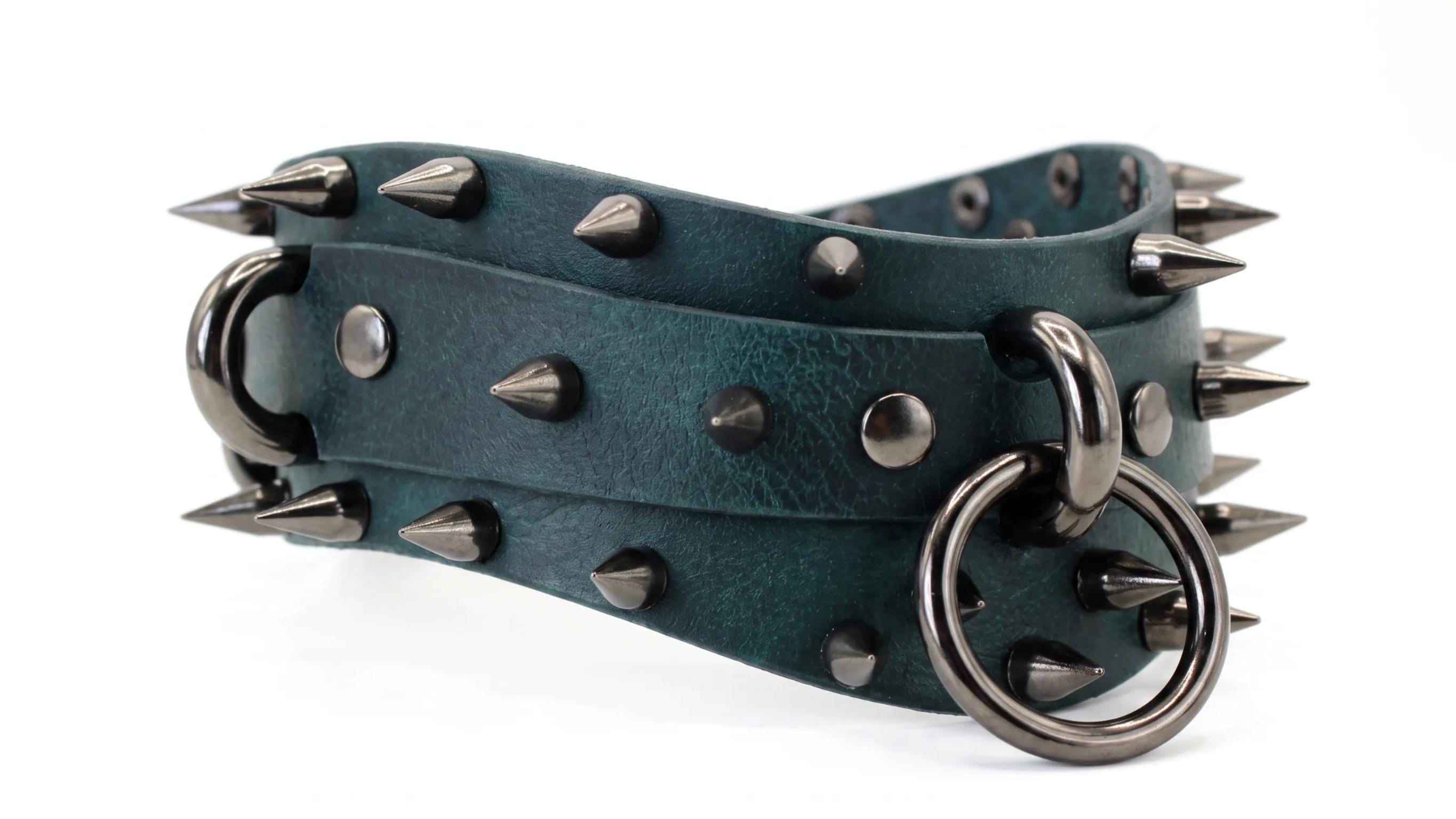 A close-up image of a green leather belt with spikes and metal rings.