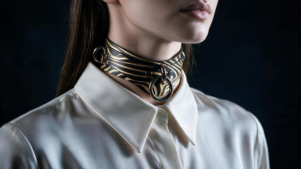 A close-up of a woman wearing a white collared shirt with a black and gold zebra print choker necklace.