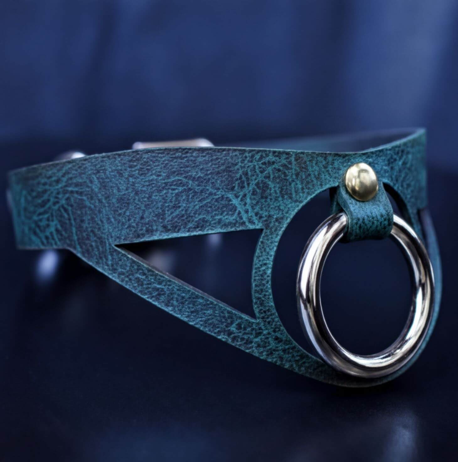 A close-up view of a green leather choker necklace with a metal ring and a silver buckle.