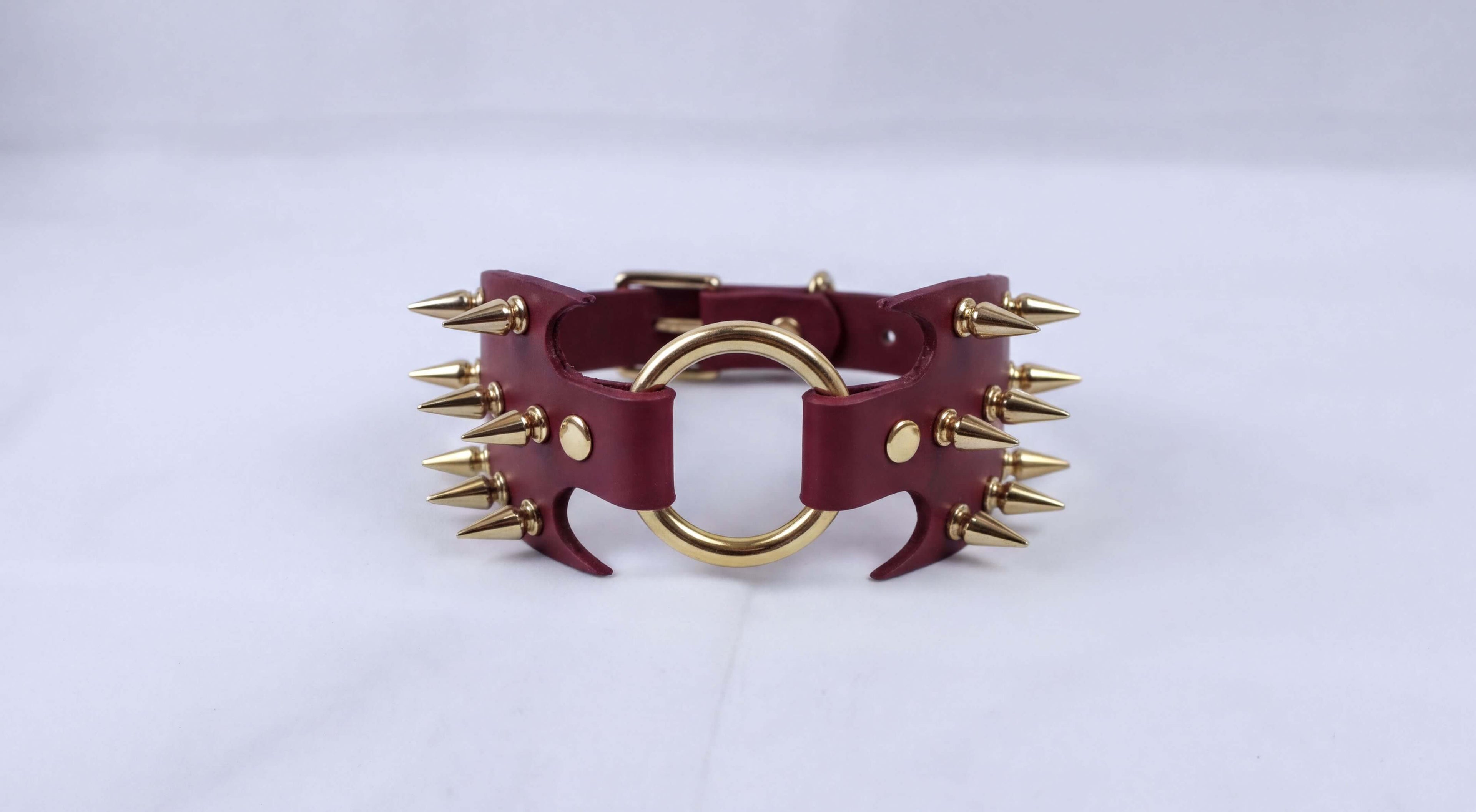 A burgundy leather choker necklace with gold spikes protruding from the clasp.