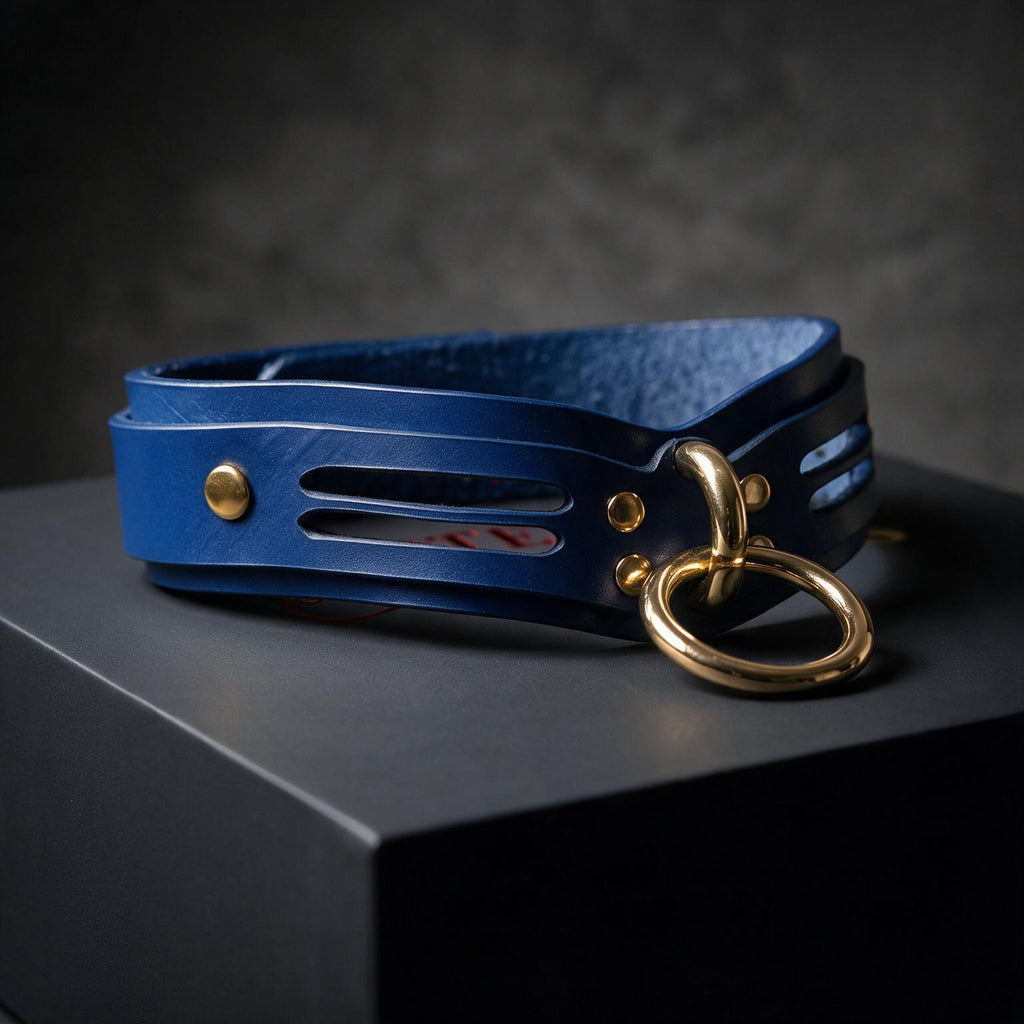 A blue leather choker necklace with a gold ring and buckle is displayed on a black surface.