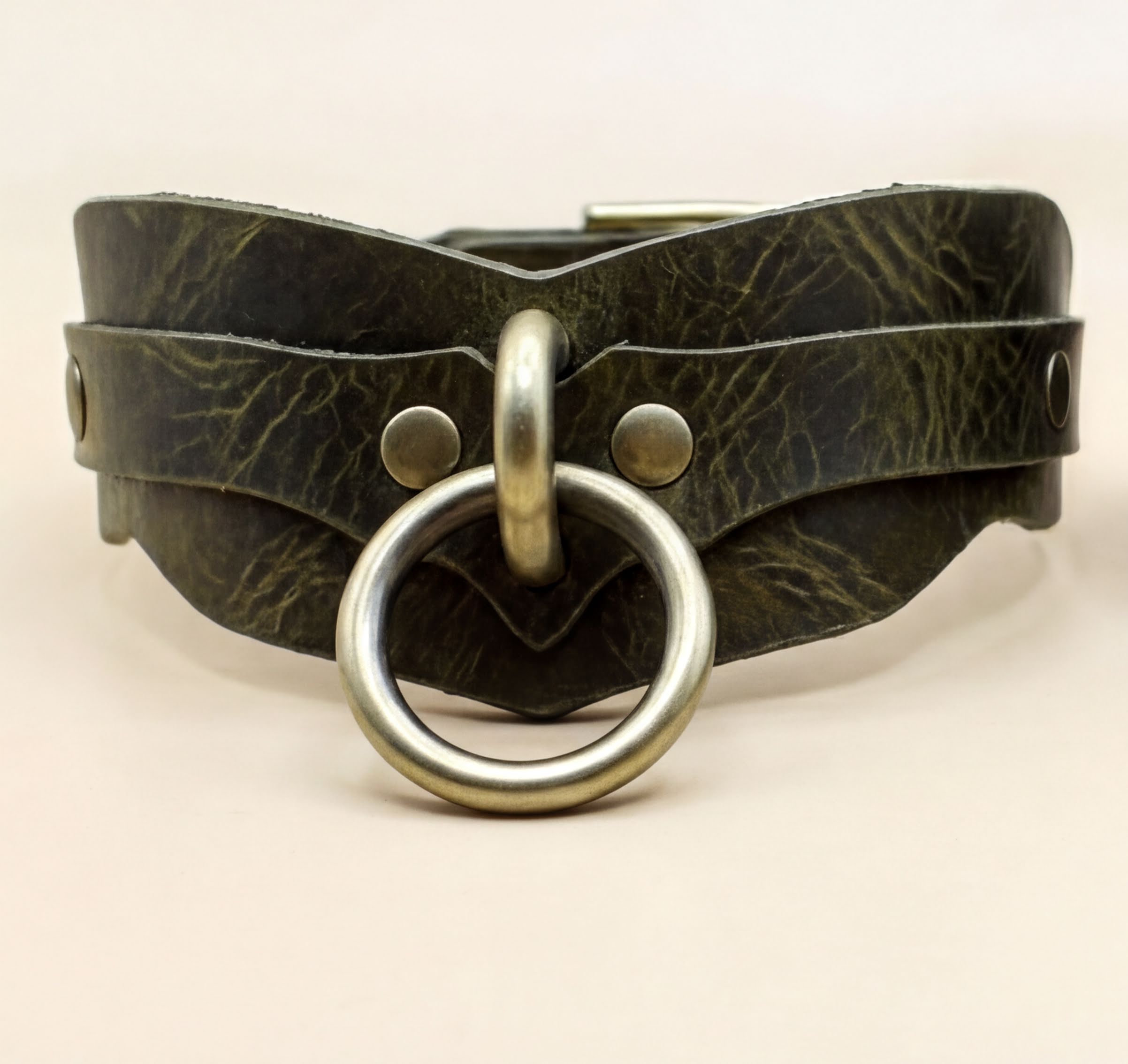 A close-up image of a leather choker necklace with a metal ring and buckle.