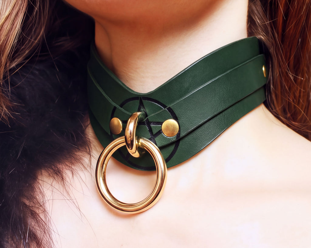 A close-up of a person's neck wearing a green leather choker necklace with a gold ring.