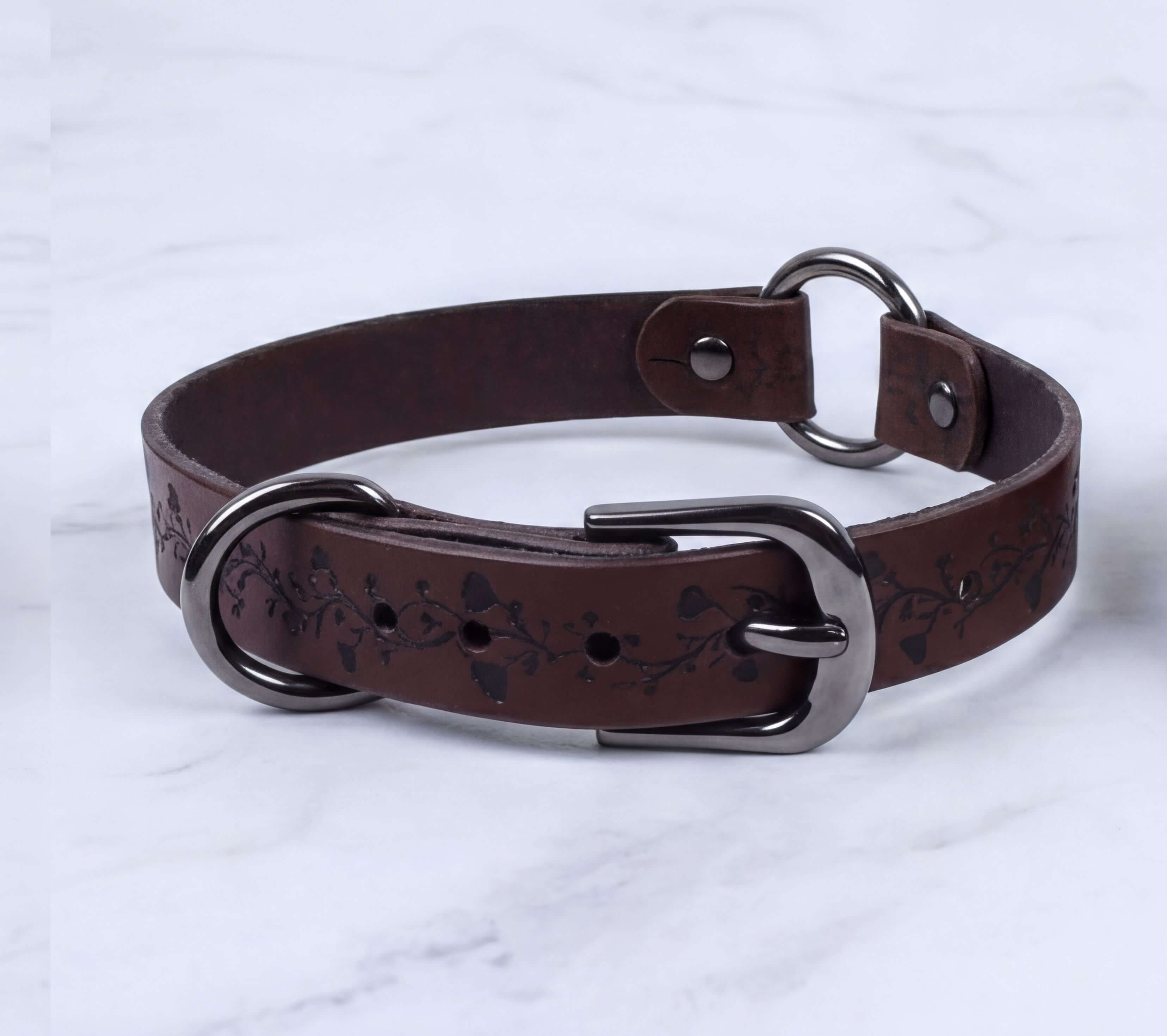 A brown leather collar with a metal buckle and a floral pattern on the strap.