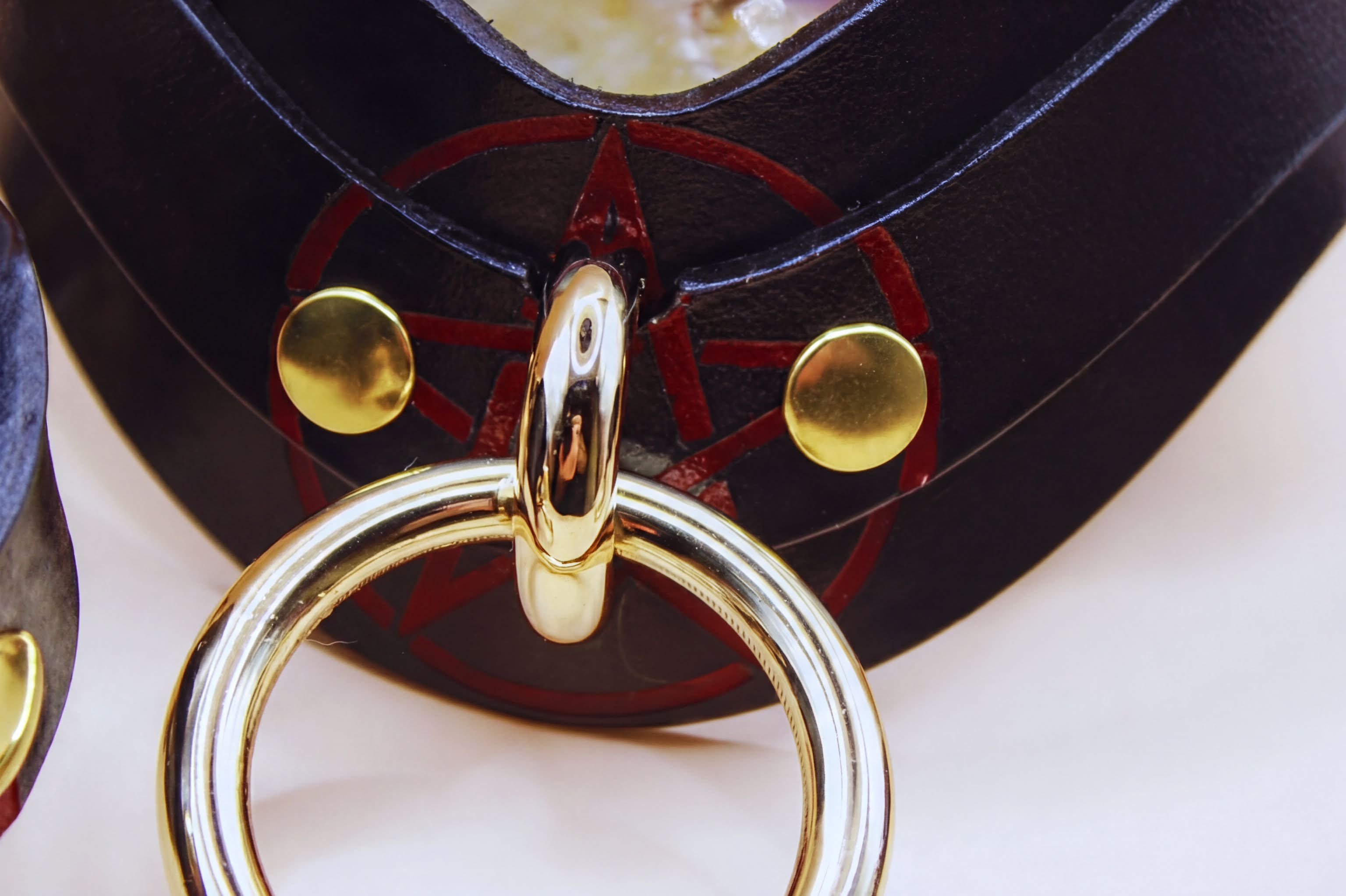 Close-up of a luxurious BDSM collar featuring a pentagram symbol and gold hardware, ideal for submissive play.