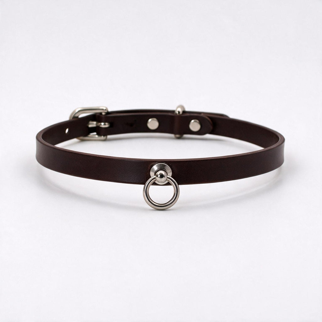 A brown leather choker collar with a metal ring and buckle.