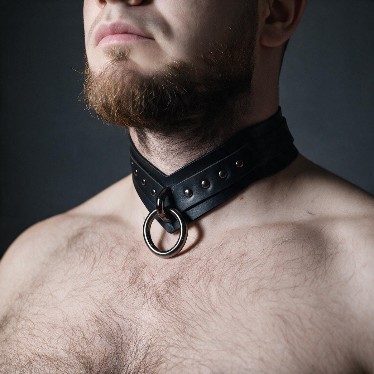 A close-up of a man's chest wearing a black leather choker necklace with a metal ring.