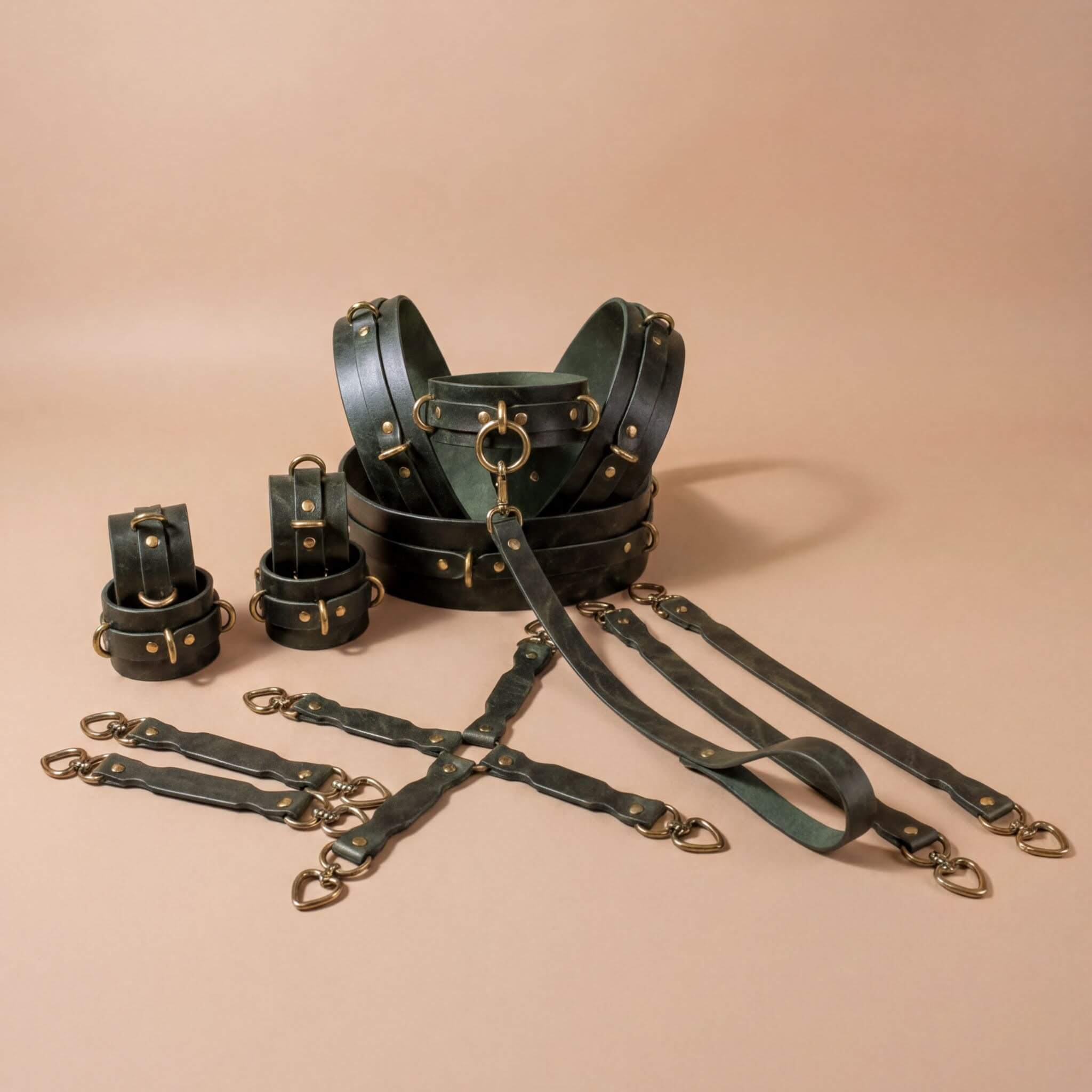 A collection of leather straps and buckles in a dark green color, arranged on a beige background.
