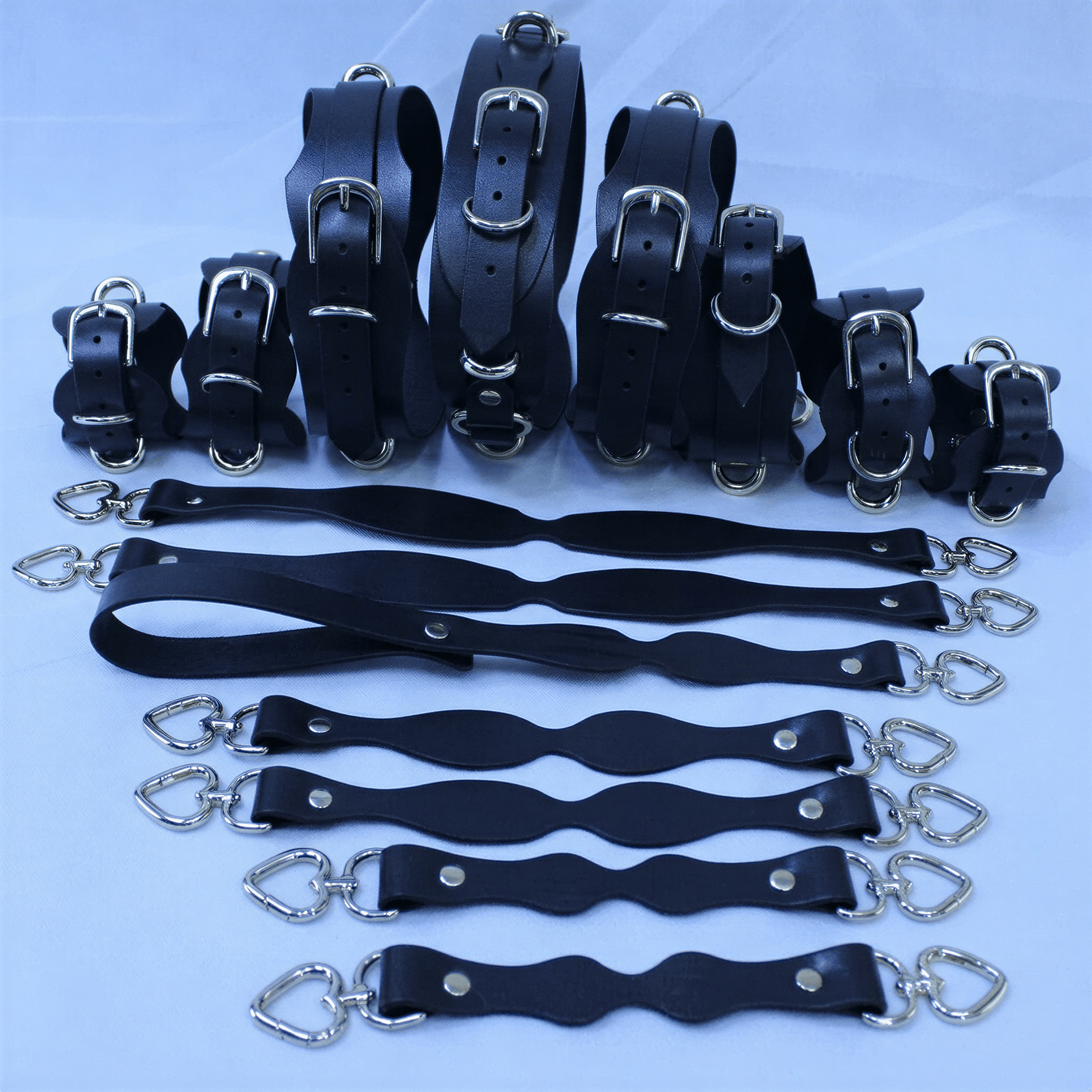 A collection of black leather straps with silver buckles, arranged in rows on a white background.