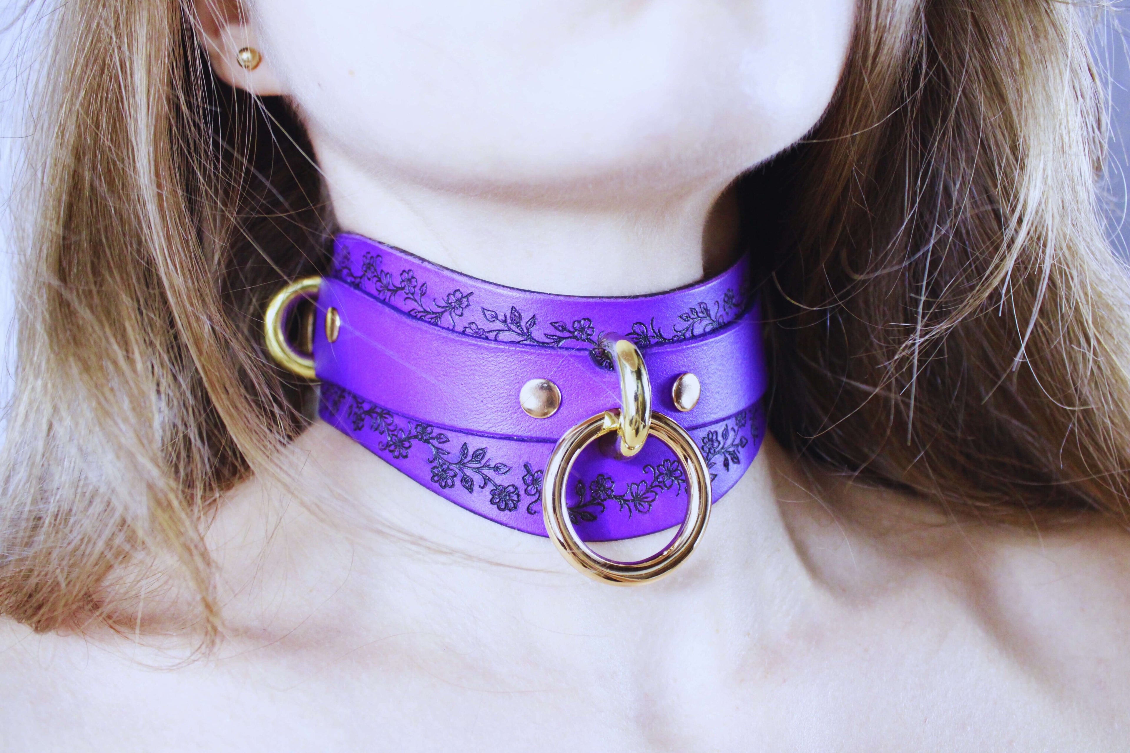 Purple Leather Floral Choker with gold rings, featuring floral motifs, worn elegantly around the neck.