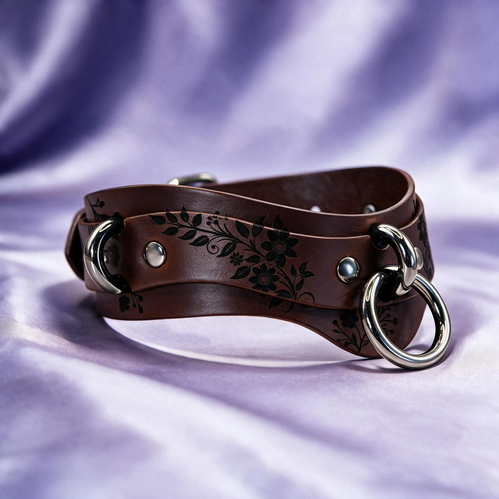 A brown leather choker with metal rings and a floral design on the surface.