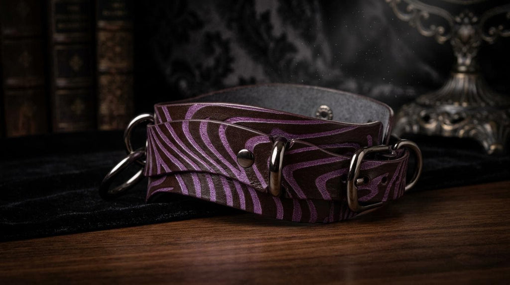A purple zebra-striped leather strap with metal buckles is displayed on a wooden surface, with a bookshelf and a lamp in the background.