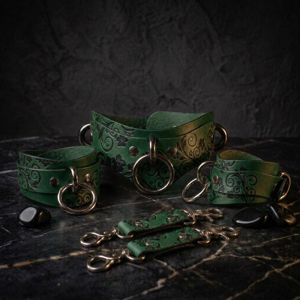 A collection of green leather straps with metal rings and decorative patterns, arranged on a dark surface.