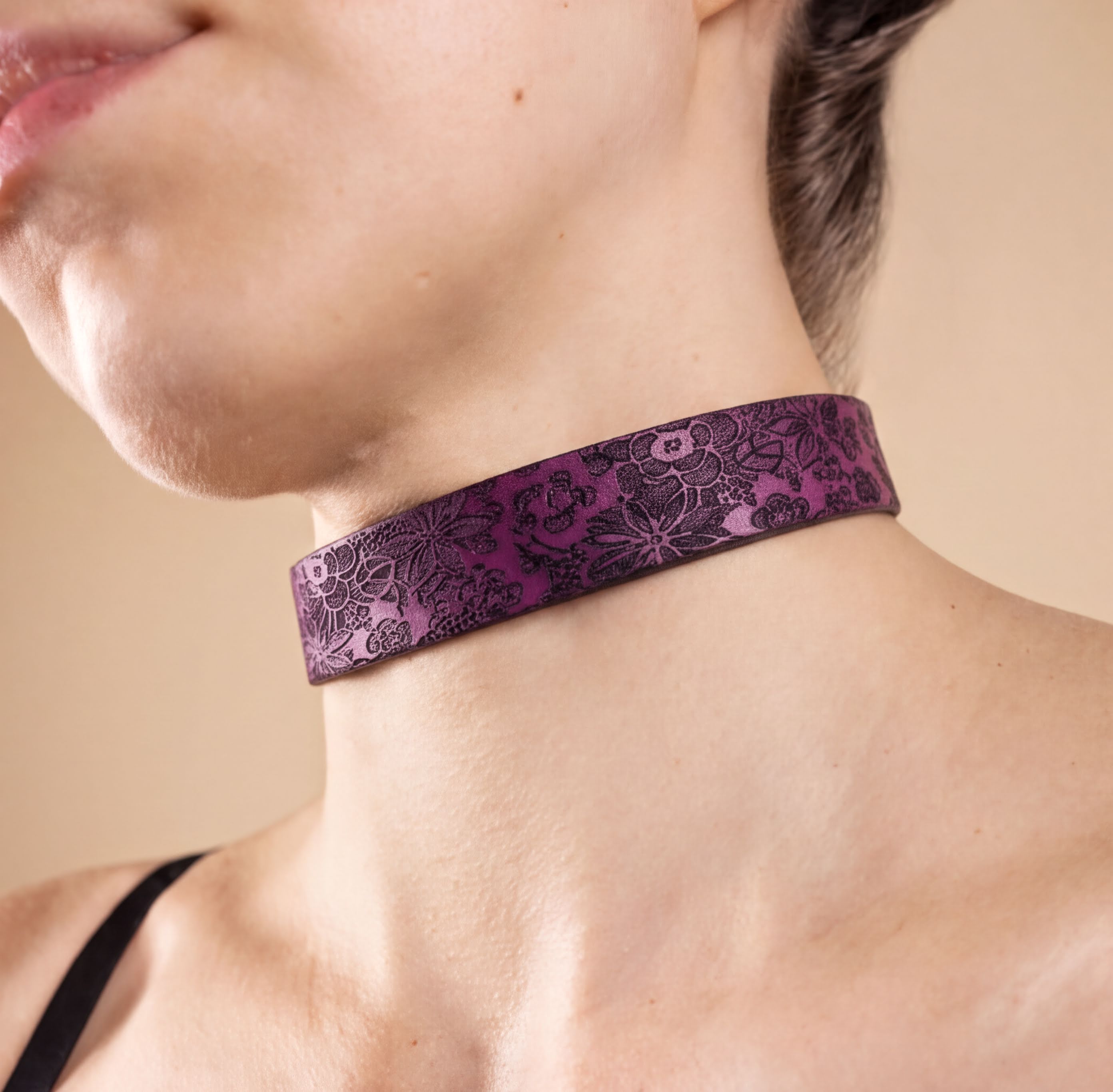 A close-up of a person's neck and chest area wearing a purple choker necklace with a floral pattern.