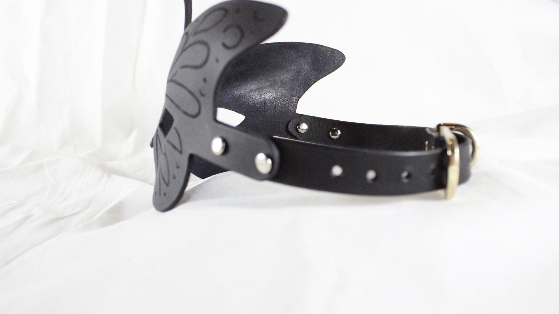A black leather headband with a decorative butterfly design is shown against a white background.