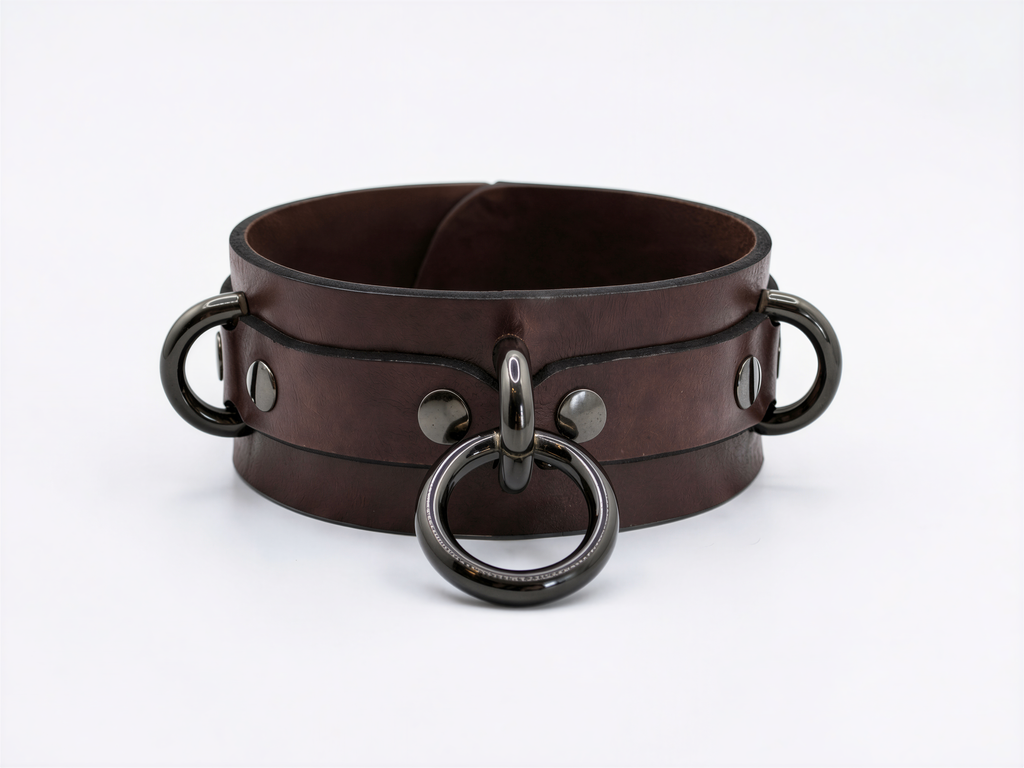 A brown leather choker collar with metal rings and handles.