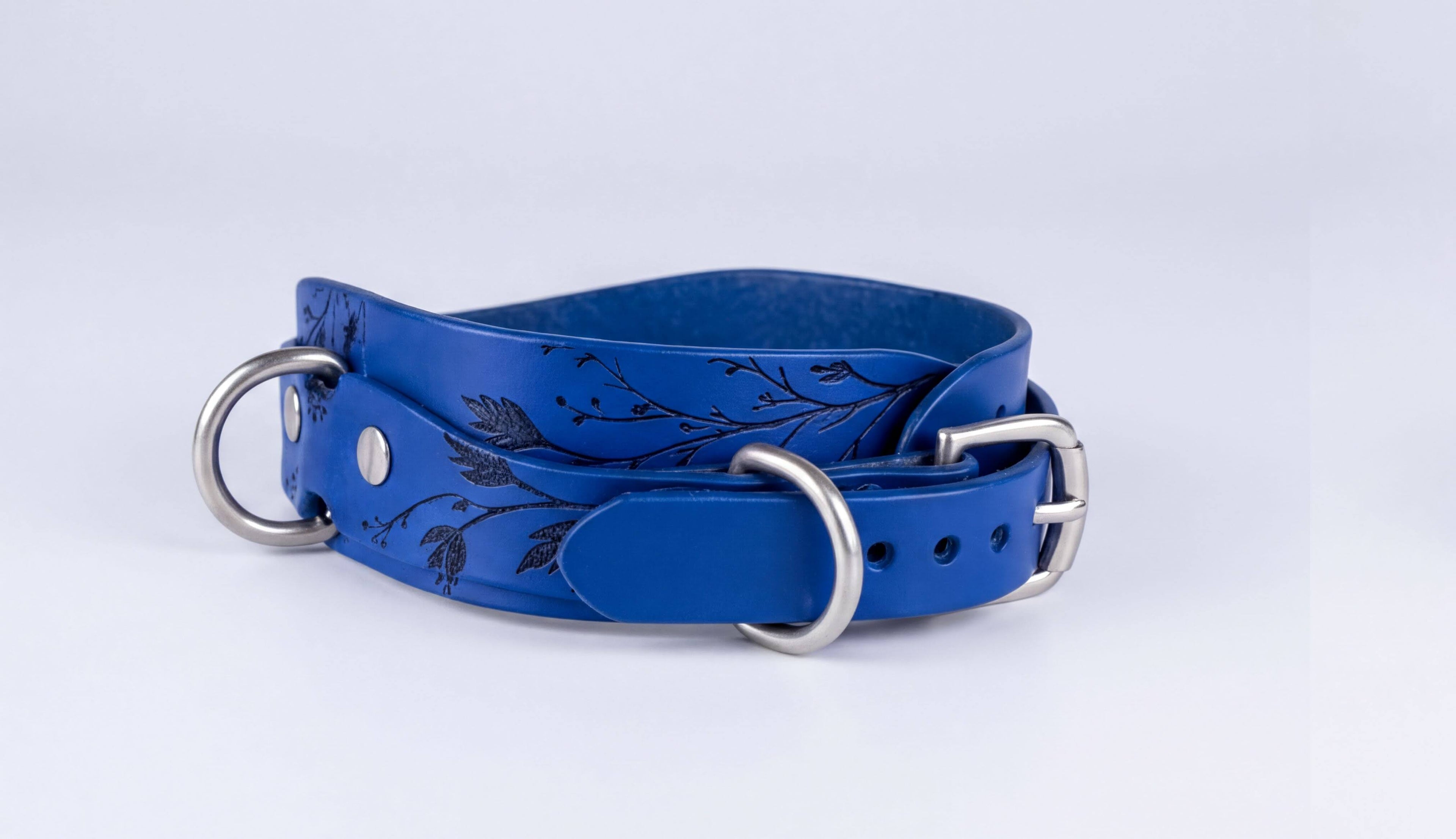 A blue leather belt with metal buckles and a floral design on the surface.