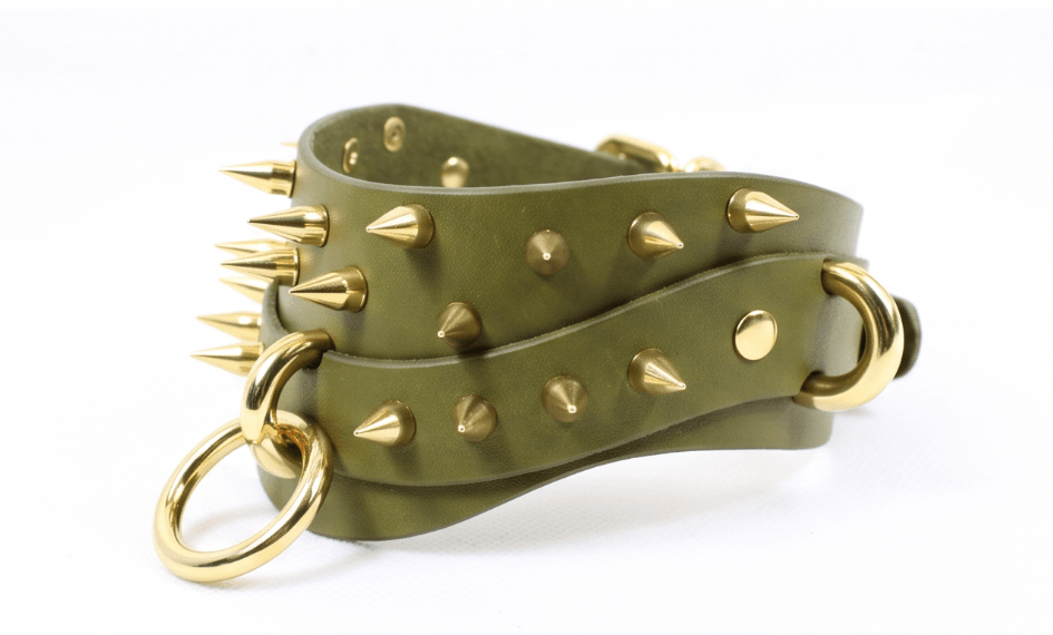 A green leather strap with gold spikes and rings, creating a bold and edgy accessory.