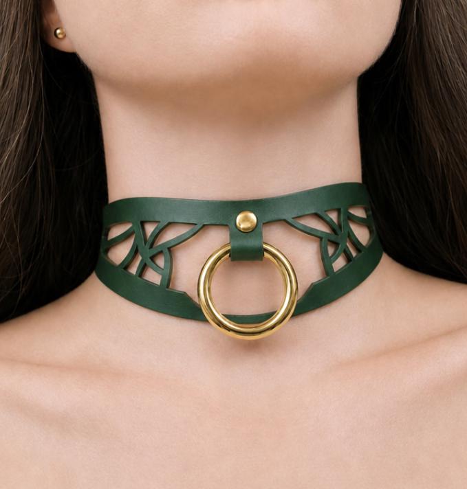 A close-up of a woman's neck wearing a green choker necklace with a gold ring.