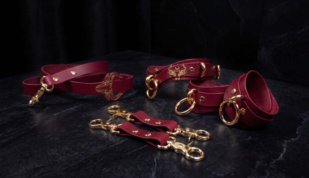 a collection of red leather straps and buckles, some of which are adorned with gold hardware. The straps appear to be designed for use in BDSM or BDSM-related activities, with the gold hardware adding a touch of luxury and elegance.