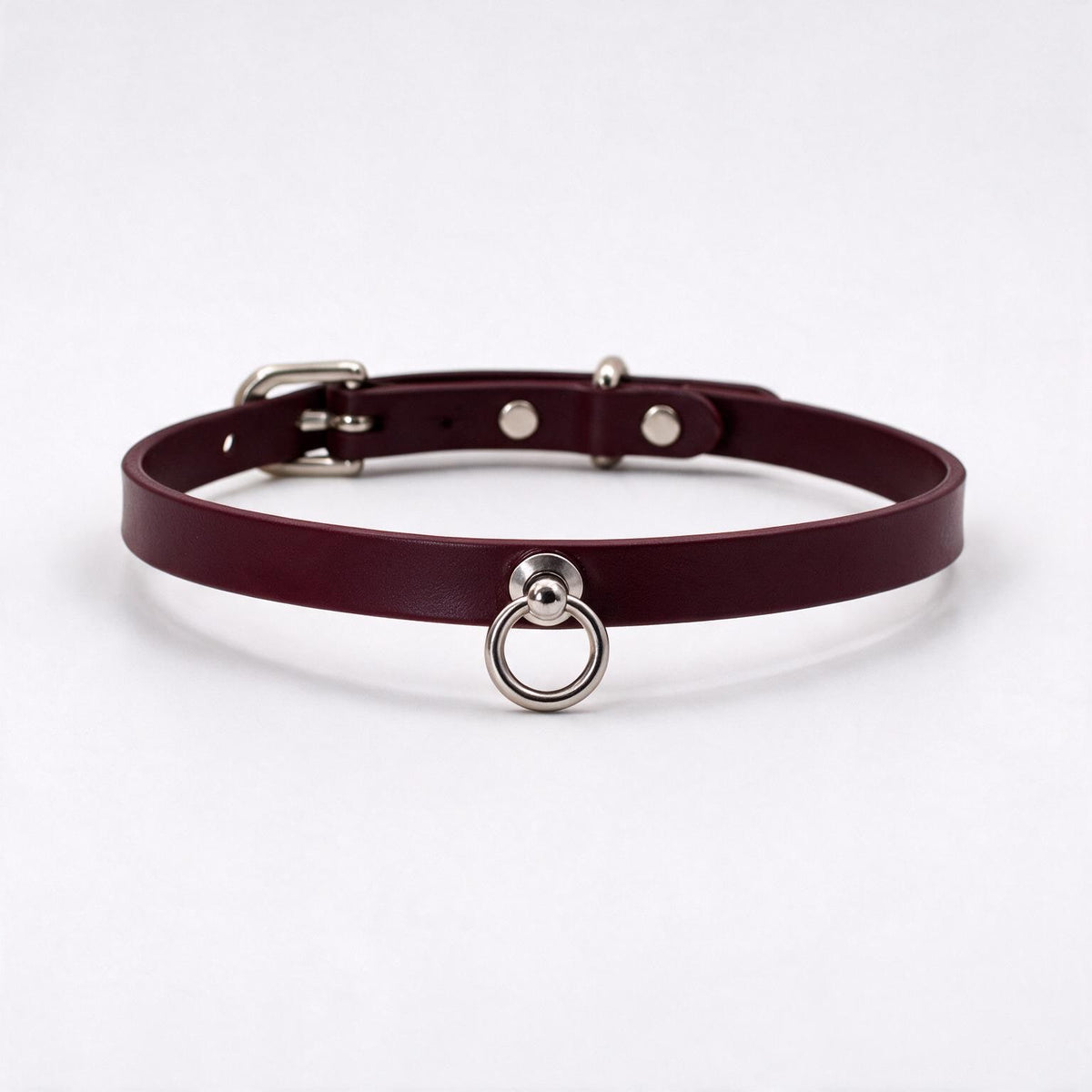 A burgundy leather choker collar with a metal ring and buckle.